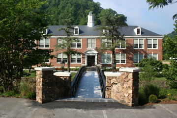 A large stone building with a clock on the side of a road