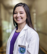 student in lab coat smiling